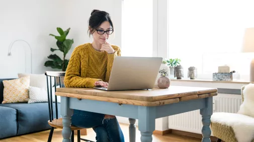 Eine Frau sitzt vor einem Computer und arbeitet zu Hause.